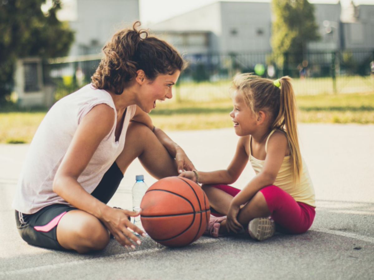 A mum and daughter laughing together on a basketball court